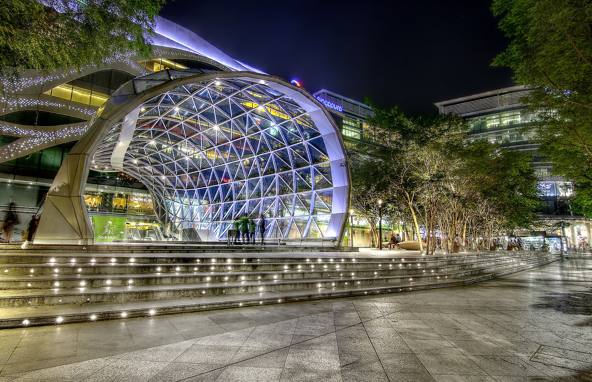 The glass front of Plaza Singapura on Orchard Road lit up at night